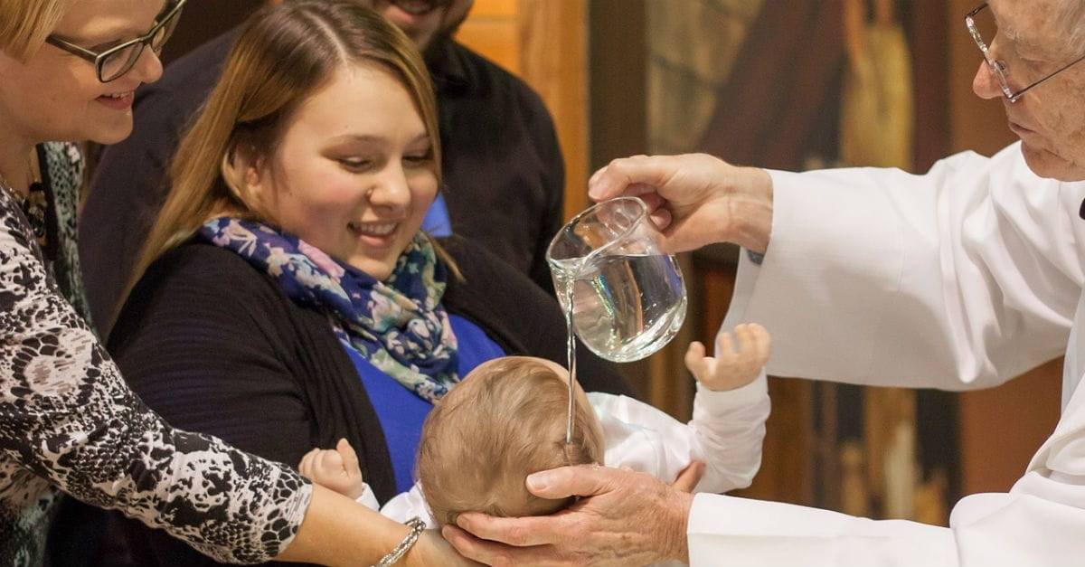 Family holding child as it is christened by priest, why christen children