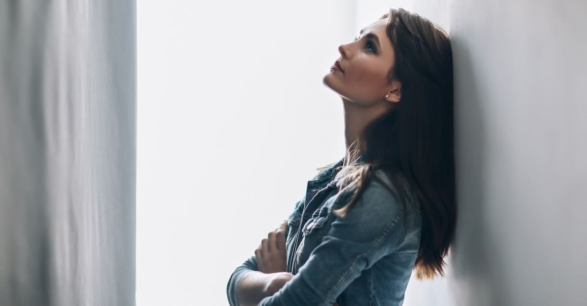 woman leaning against wall thinking