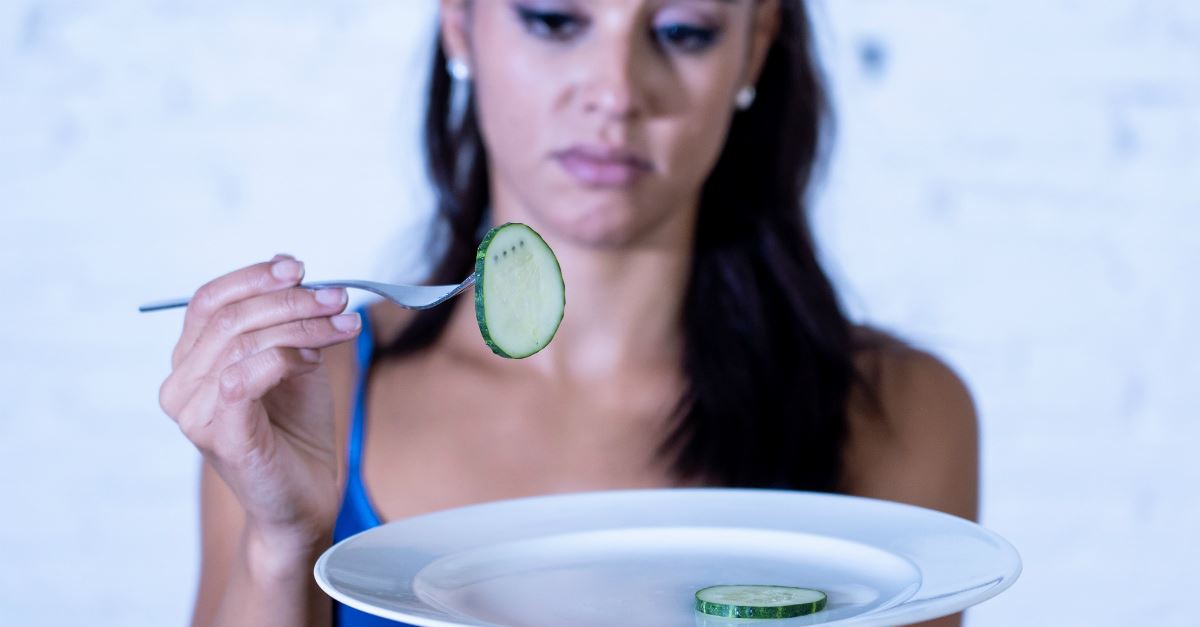 girl looking unhappy with one cucumber slice on fork