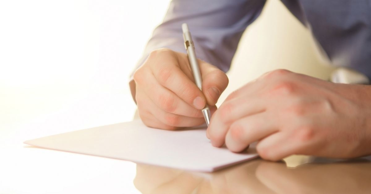 closeup of man's hands writing a note