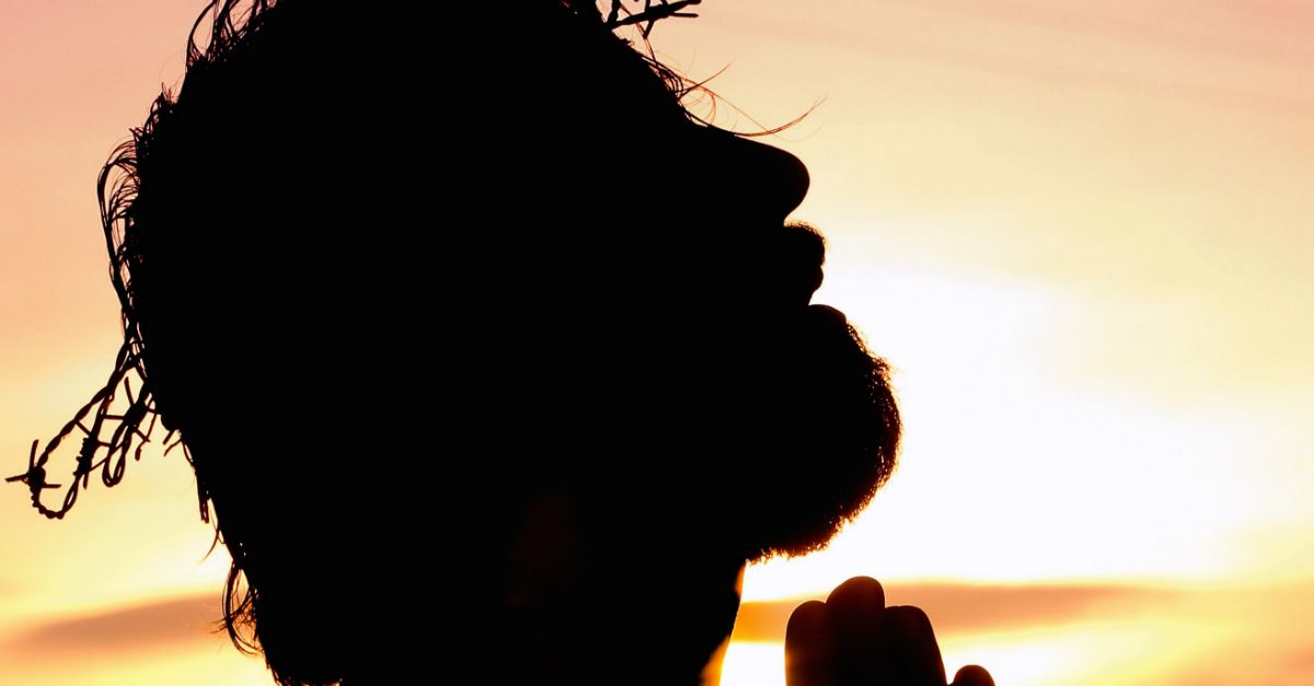 silhouette of man with crown of thorns on head, looking up, praying