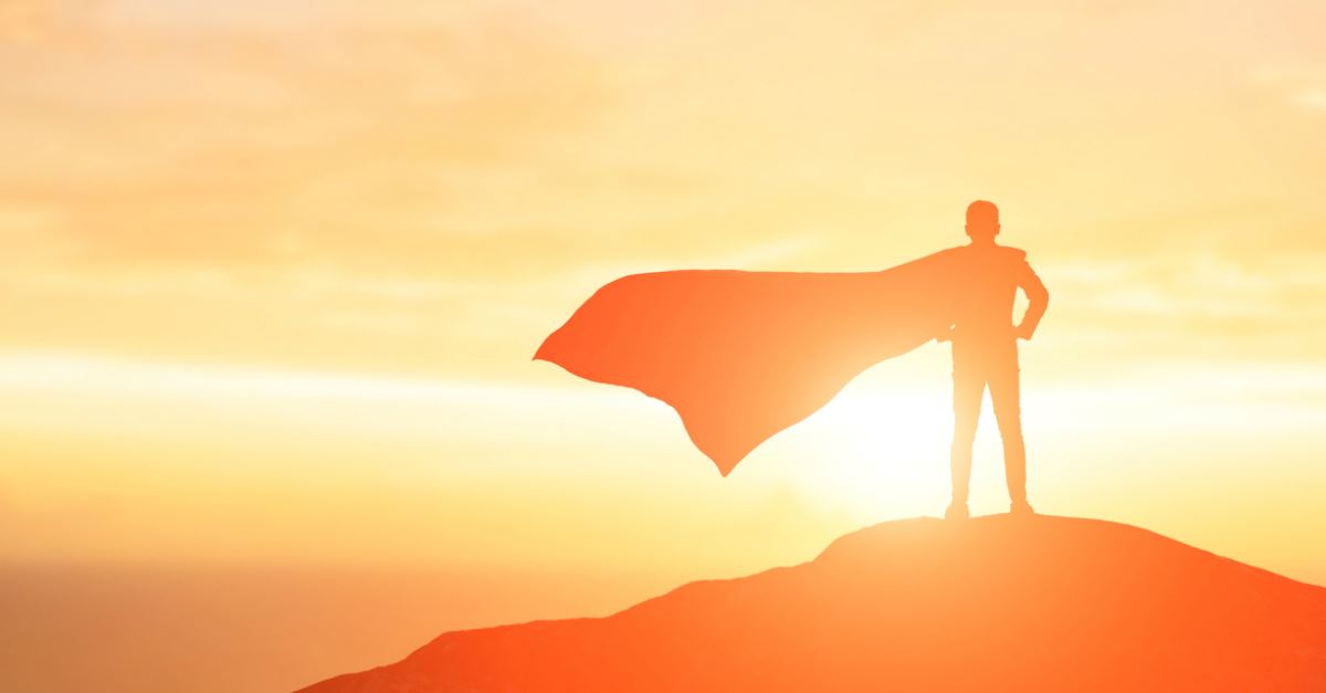 silhouette back view man facing sunrise on mountain, superhero cape blowing in wind