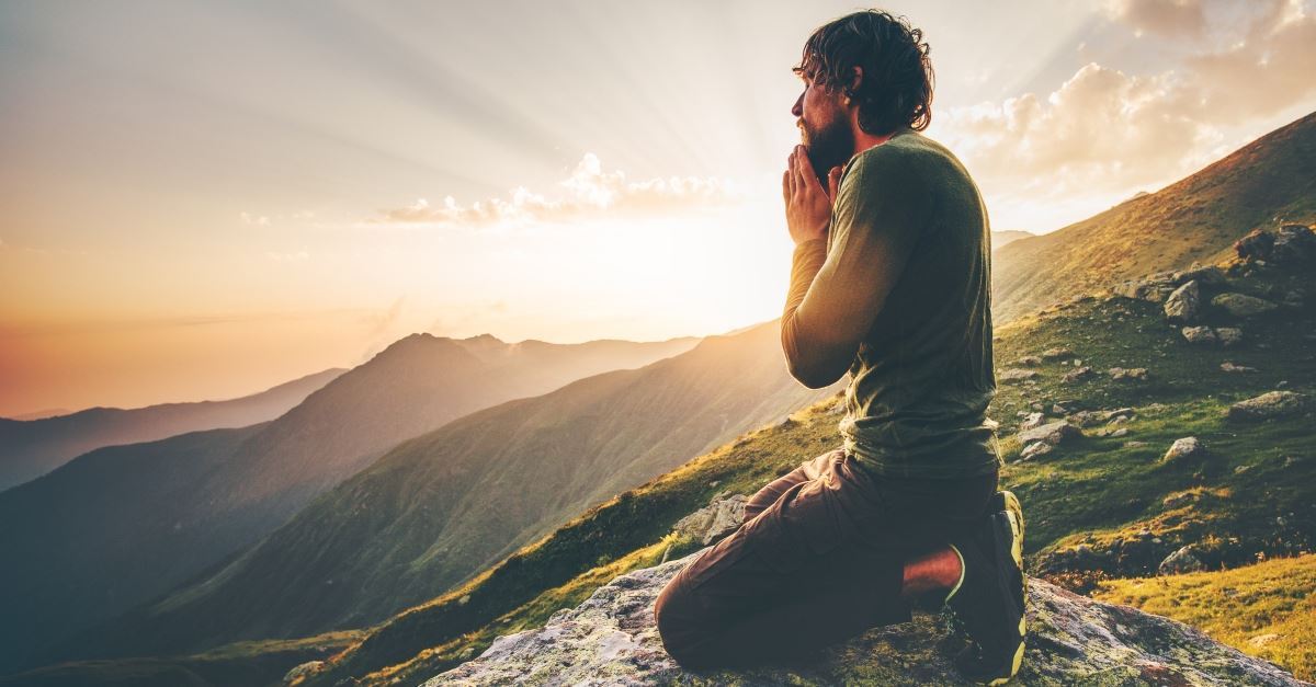 Man kneeling praying on mountain, stronghold of pride