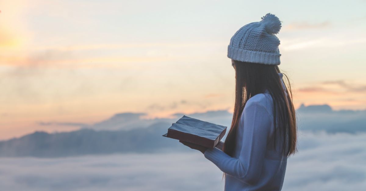 woman holding bible in mountains