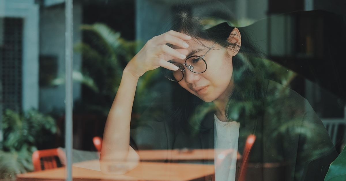 sad young woman sitting in cafe window, when to walk away from a dying friendship