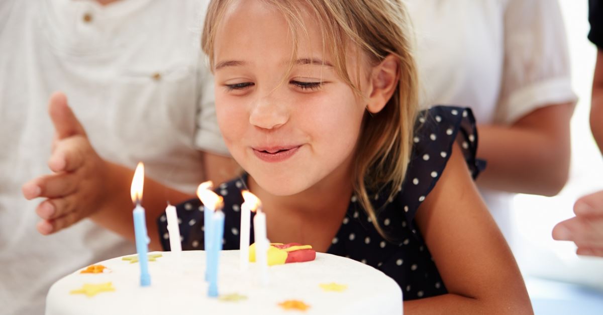 little girl blowing out birthday candles on cake