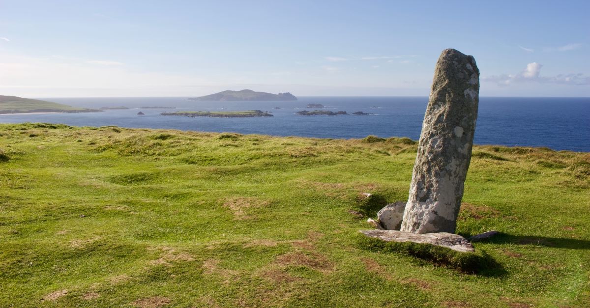 stone pillar on grassy cliff top, lighten your load with pile of stones