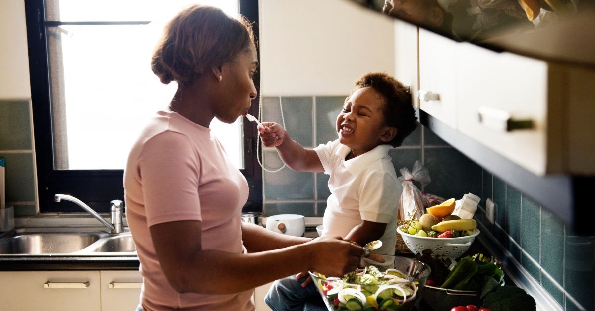 child feeding mom smiling sitting on kitchen counter, redefining organization