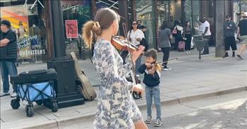 <p>Violinist Karolina Protsenko, joined here by an adorable 2-year-old, is mesmerizing!</p>

<p>Karolina Protsenko, born October 3, 2008 in Ukraine, is the daughter of two musicians, Nikolay and Ella Protsenko. Karolina moved with her parents to the United States in 2015 when she was just six years old, and she began violin lessons that same year. That has been time well spent, because Karolina is an incredible talent!</p>

<p>Karolina plays &ldquo;Listen to Your Heart&rdquo; by Roxette, but the word &ldquo;plays&rdquo; is painfully inadequate to describe the superb musical gifts and artistry that Karolina demonstrates.&nbsp;</p>

<p>Watch as she moves effortlessly up and down the street, her steps as flowy as the skirt of her white and gray dress. Karolina often does street performances, which must be tremendous training. Staying focused amid so many distractions certainly has to be a challenge!&nbsp;</p>

<p>Two little helpers join her for this number, but their presence doesn&rsquo;t phase Karolina. That may be because the two are her younger brothers, <a href="https://biographyresearch.org/what-happened-to-karolina-protsenko-what-is-she-doing-now/">Nicolas and Leo</a>. Born in 2020, Nicolas is the younger of the two. A guitar dangles around his sweet neck, and, at least initially, he wanders in the general area of Karolina&rsquo;s tip basket. Leo is a bit more stationary, and he&rsquo;s also more engaged with his instrument.</p>

<p>However, Karolina is not merely engaged&mdash;instead she acts as one with her violin. She looks like she could as easily be a ballerina as a violinist, because her movements are so in sync with the rhythm, notes, and feel of the music. Her violin seems almost like another appendage!&nbsp;</p>

<p>At 1 minute, Karolina bends down and plays directly to Nicolas. Then, she stands and sashays around him, not once during the performance losing track of him and stumbling over the little tike. That&rsquo;s a talent all by itself!</p>

<p>Karolina twirls, skips, dips, kicks, and spins, and she delivers breathtakingly beautiful sounds and smiles all the while. It is clear that she has a passion for the violin and music, in general. Her supporters are enthusiastic, too. With nearly 8 million subscribers to her YouTube channel, Karolina&rsquo;s fans are in awe of her astounding grace and talent!&nbsp;&nbsp;</p>

<p><em>&ldquo;Begin the music, strike the timbrel, play the melodious harp and lyre.&rdquo; <a href="https://www.godtube.com/bible/psalms/81-2">Psalms 81:2</a></em></p>
