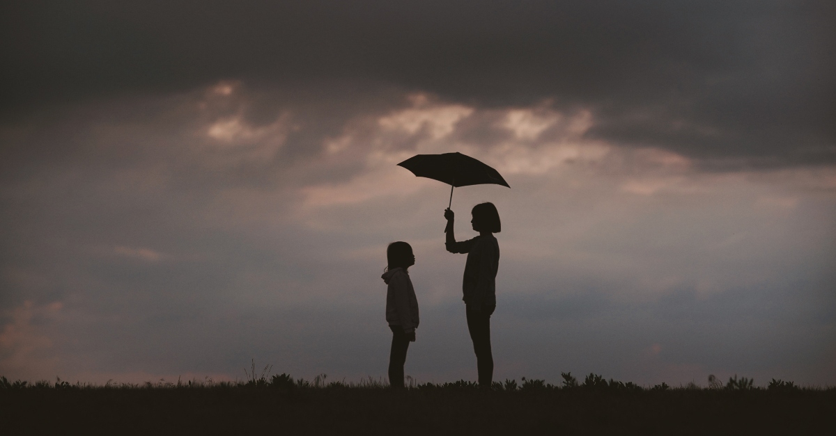 woman holding umbrella over child, god is good all the time and protects us