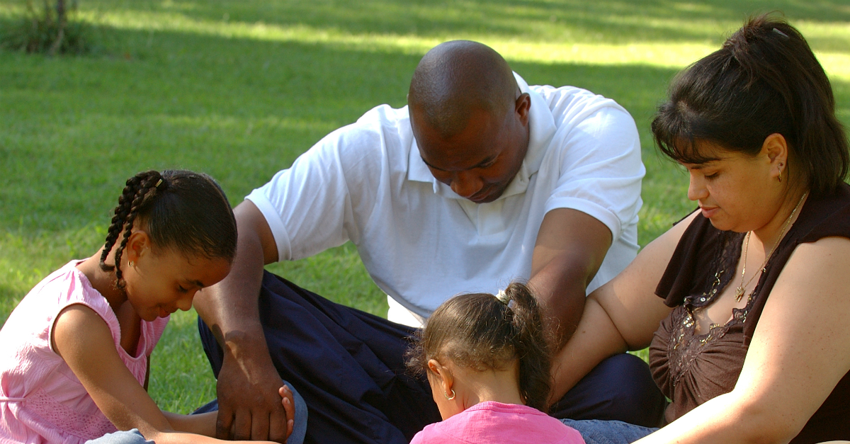 family bowing heads in prayer together in the park, with great power comes great responsibility