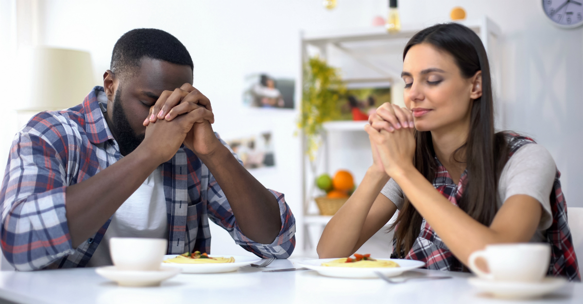 Man and woman praying over their meal together
