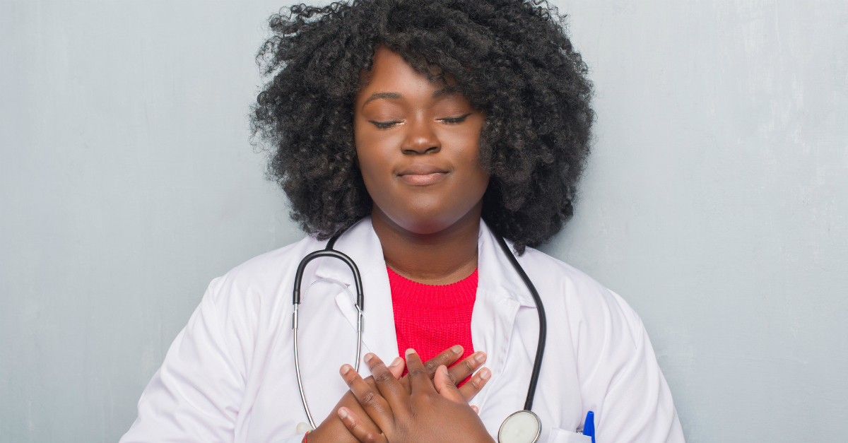 woman doctor hands over heart praying giving thanks