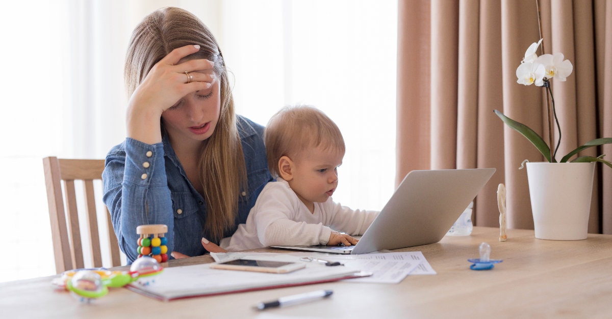 mother exhausted watching toddler on computer