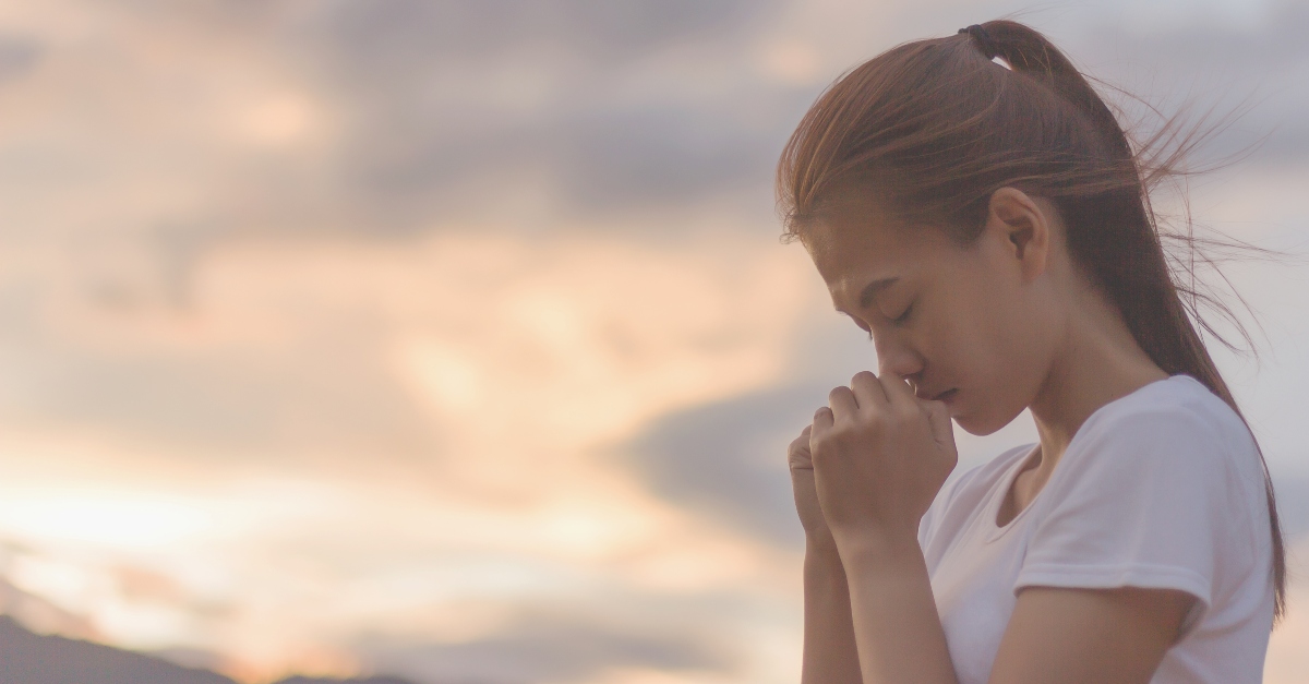 young woman praying outside against beautiful sky background, prayer for forgiveness