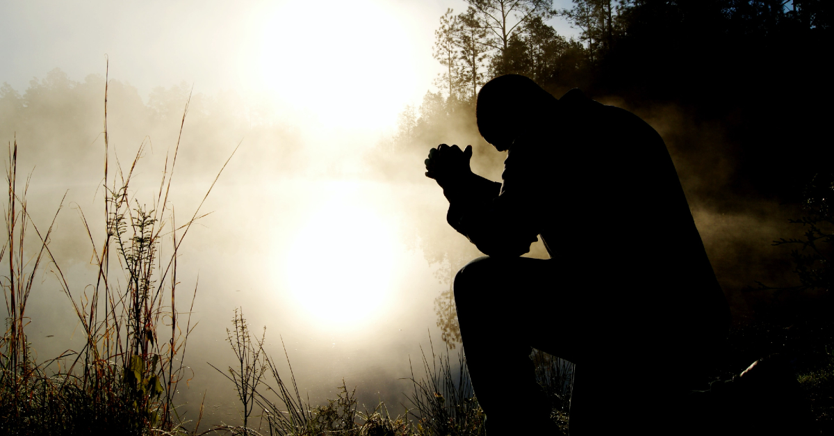Man kneeling outside in prayer
