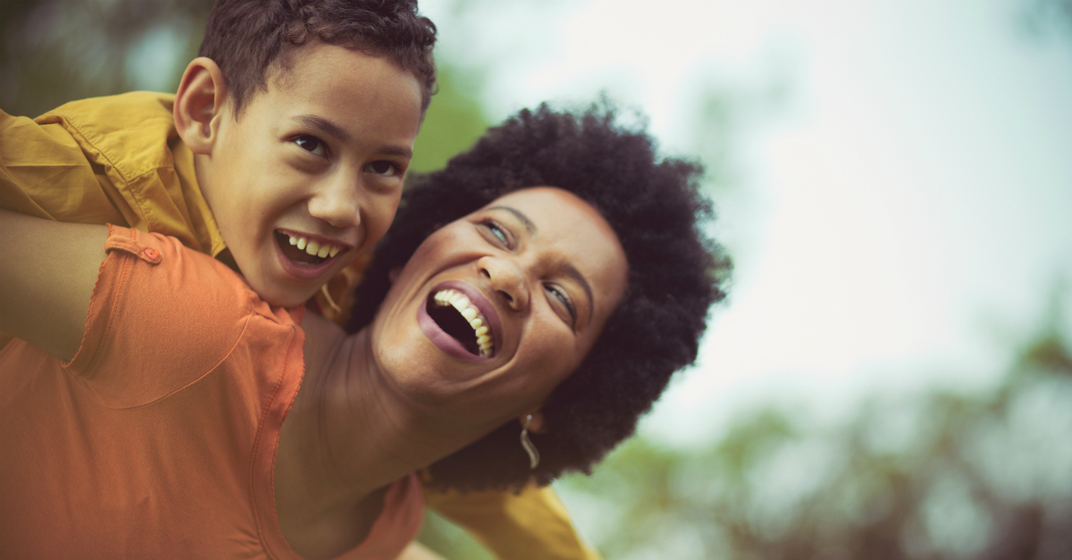 mom giving young son a piggyback smiling joy