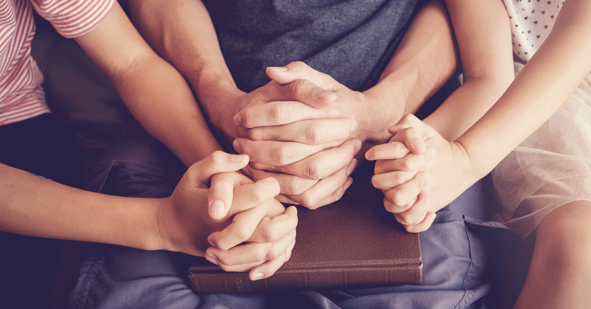 family holding hands over bible