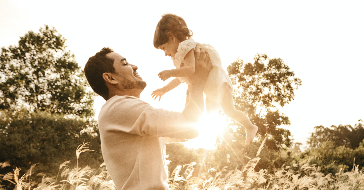 happy dad with kid in flower field sunset