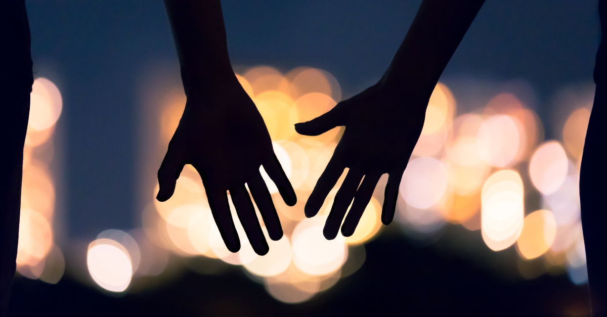 silhouette of hands reaching against city lights backdrop, things to stop taking for granted after pandemic