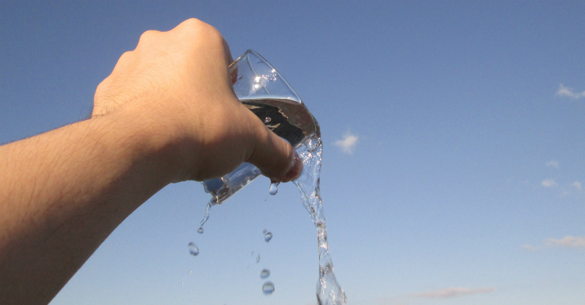 hand toward sky pouring out water from glass