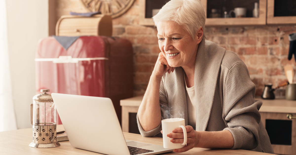 senior woman happily watching video on laptop computer