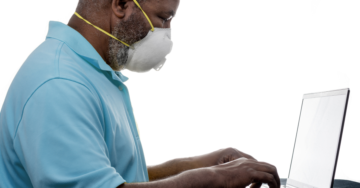 elderly man with face mask on at laptop computer