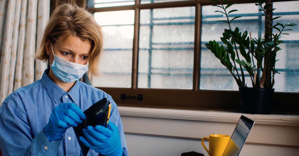 worried woman looking in wallet with face mask on coronavirus