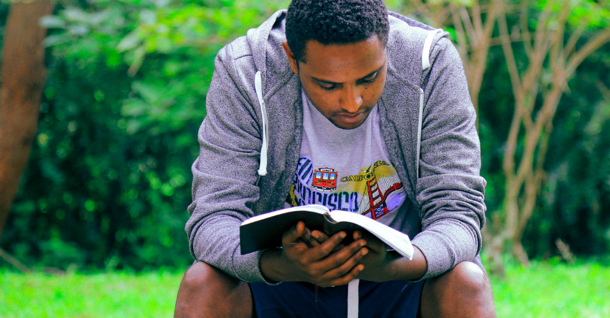 man reading bible outdoors