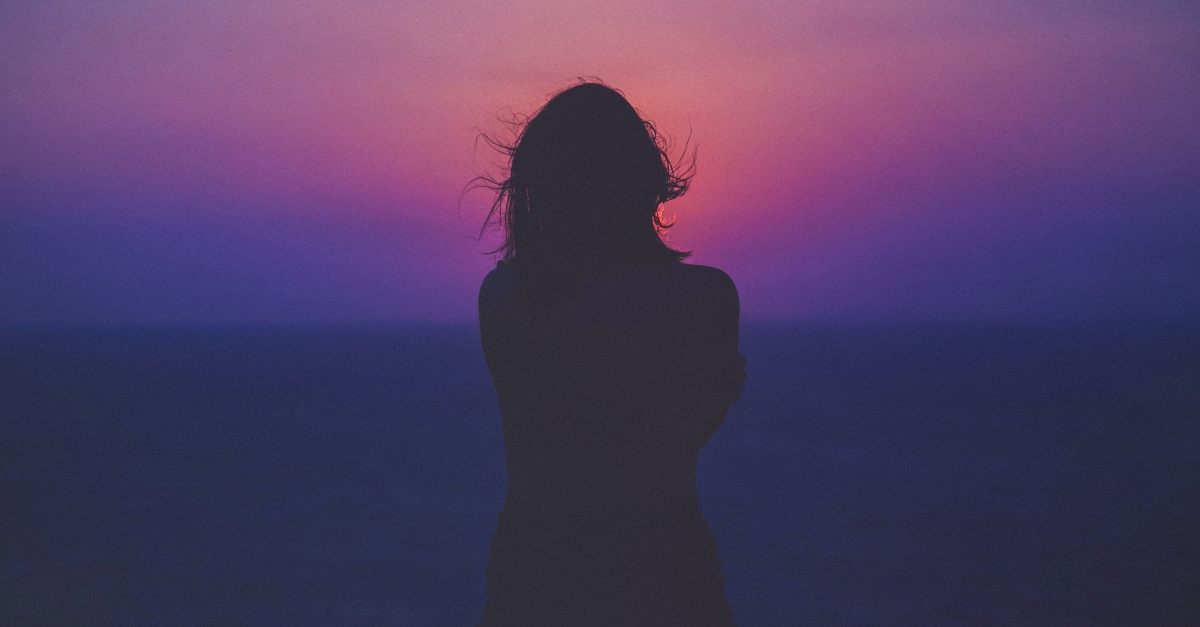 woman silhouette standing in front of ocean sunset sunrise