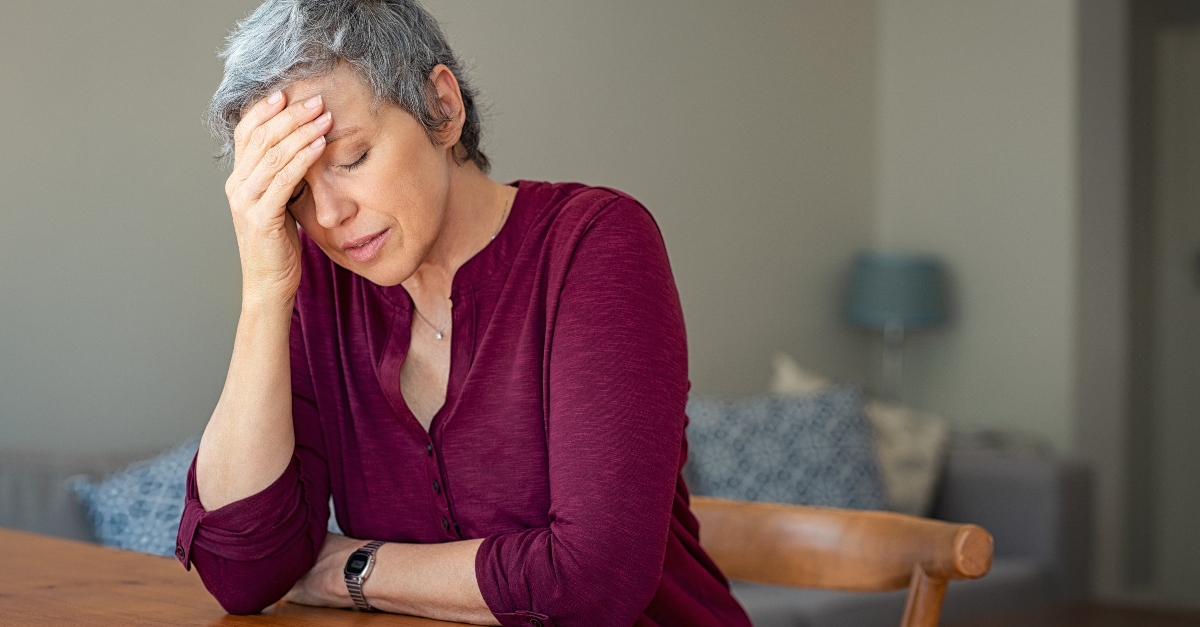 senior woman looking discouraged or tired with eyes closed and head in hand, spiritually asleep