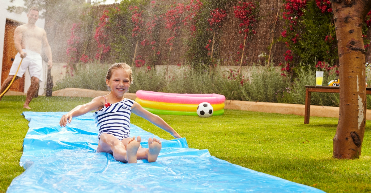a girl sliding down the slip in slide in her backyard