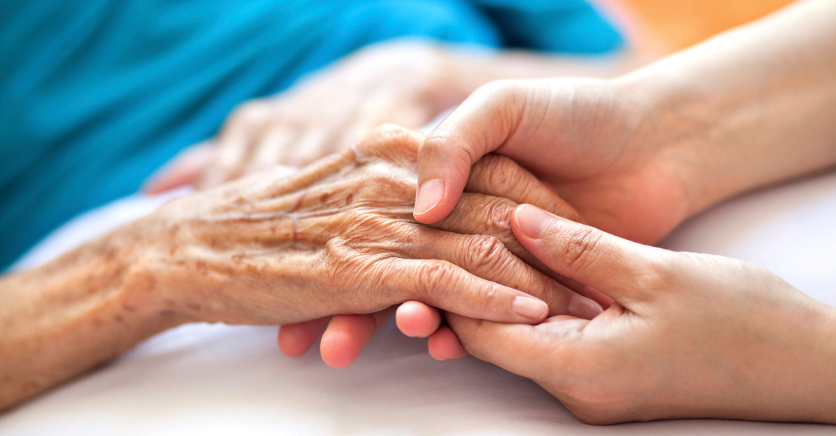 holding hand of elderly anointing of sick