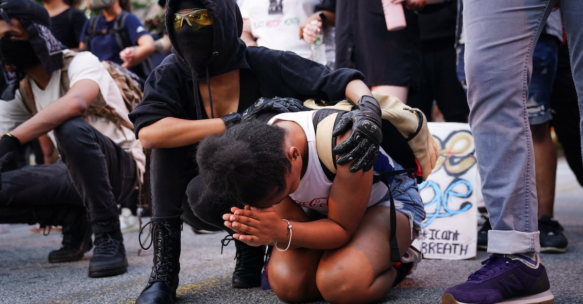 Protestor praying at protest with friend holding her