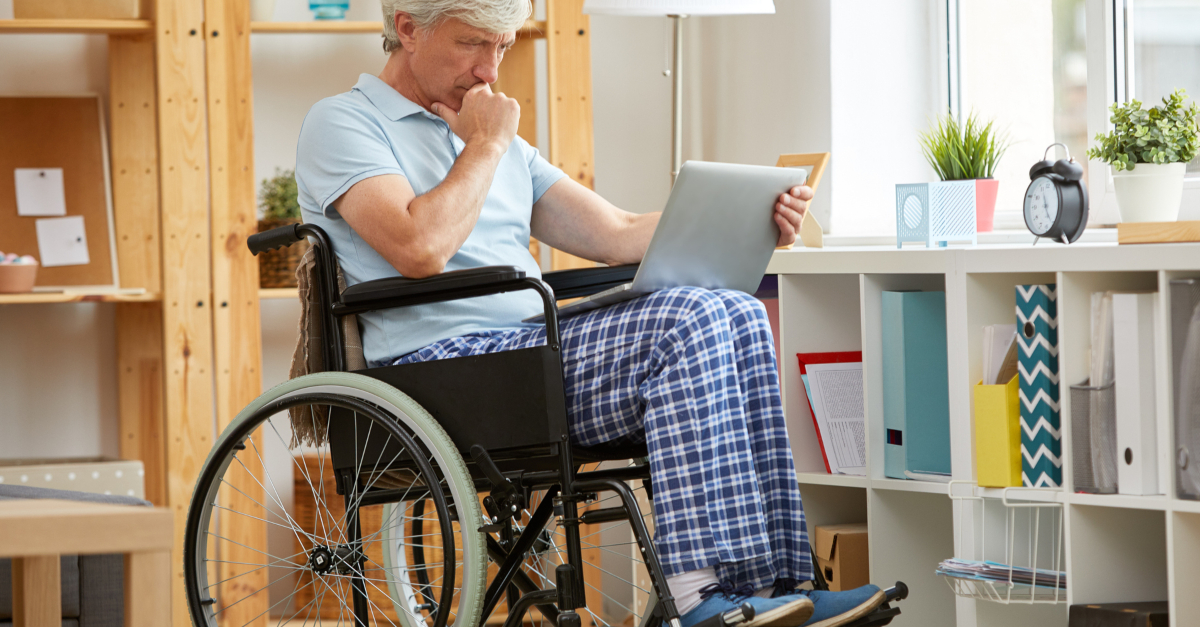 senior man in wheelchair watching church online on laptop