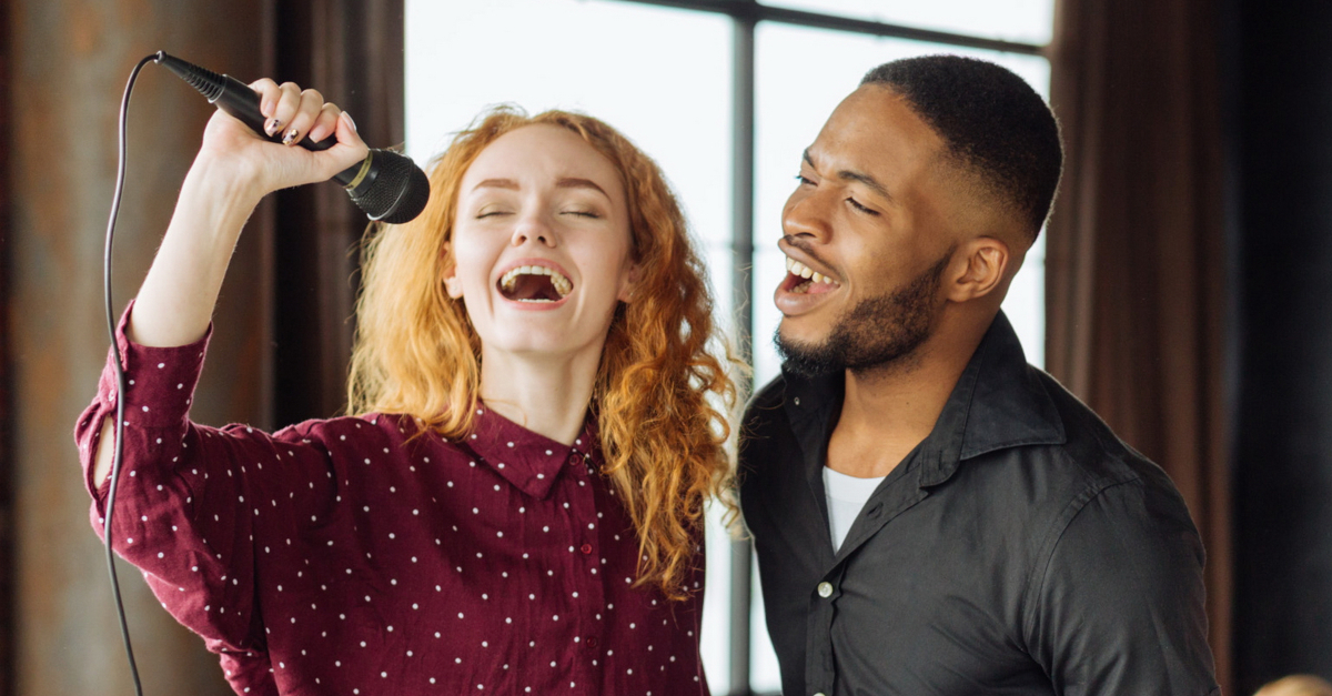 woman and man singing joyfully into microphone worship