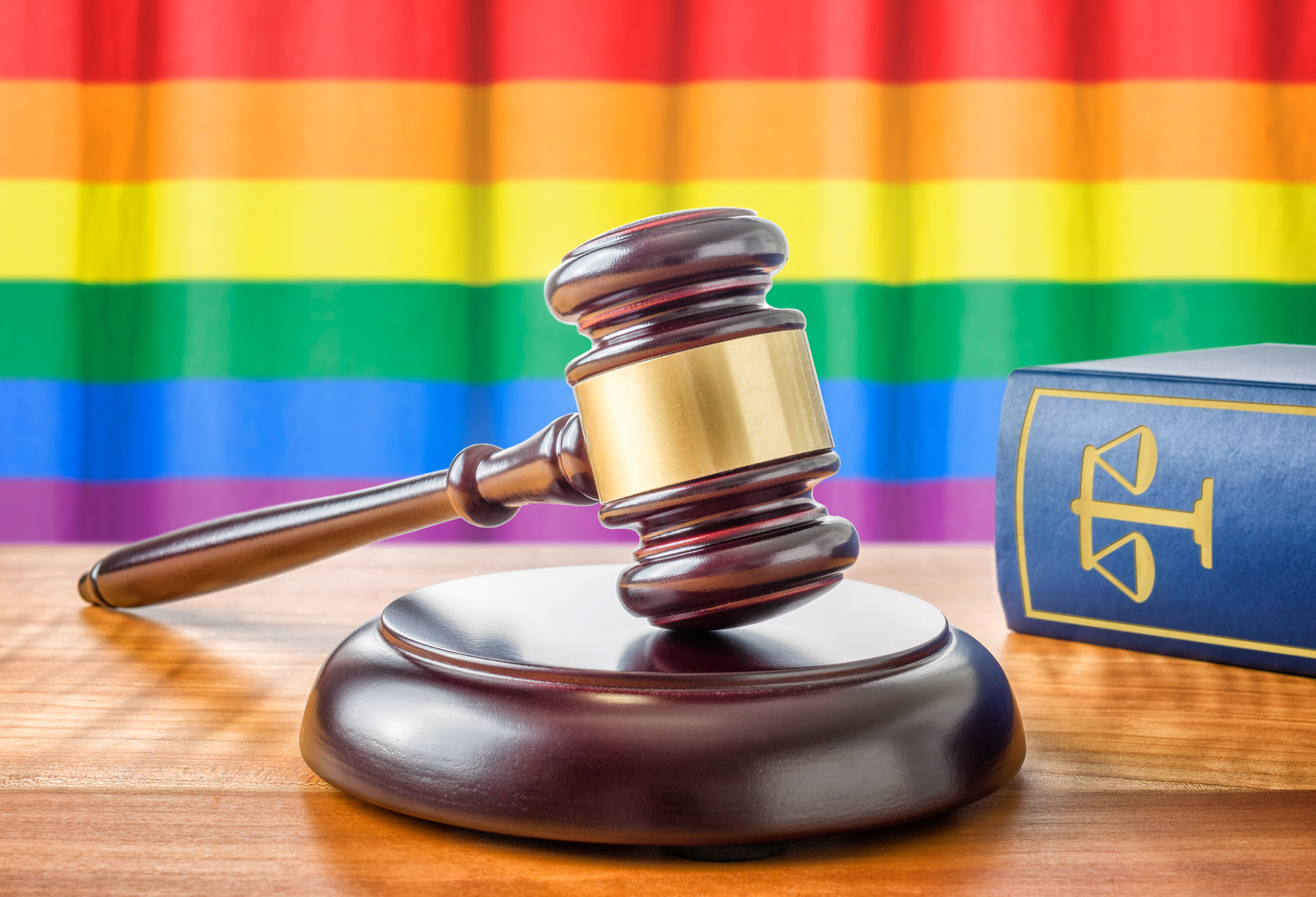 gay rainbow flag behind judge gavel and law book