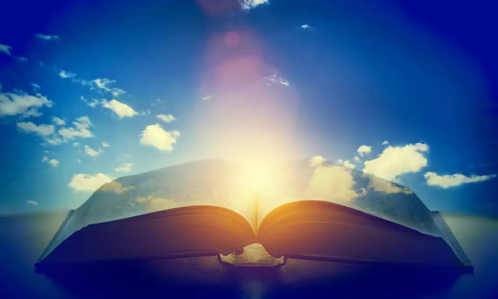 open bible with blue sky background and glow from center