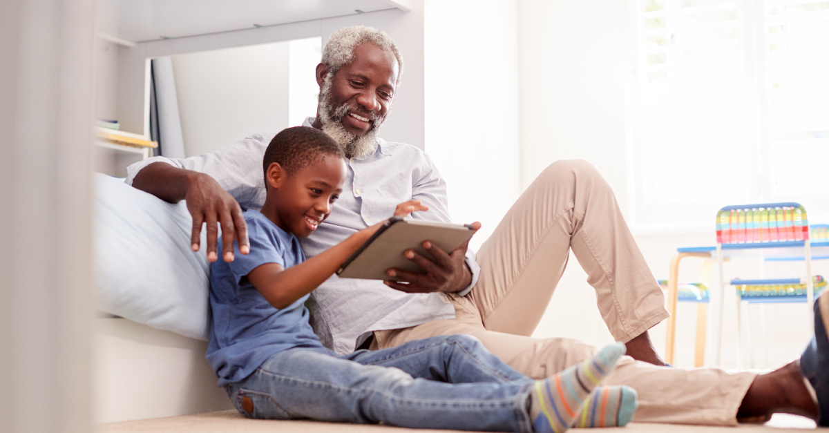 Großvater mit Kind schaut auf Tablet