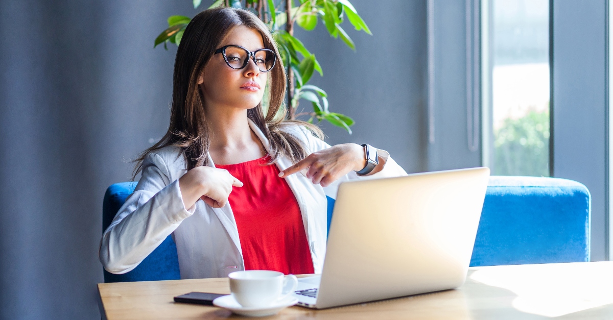 proud looking business woman working at a desk pointing to herself