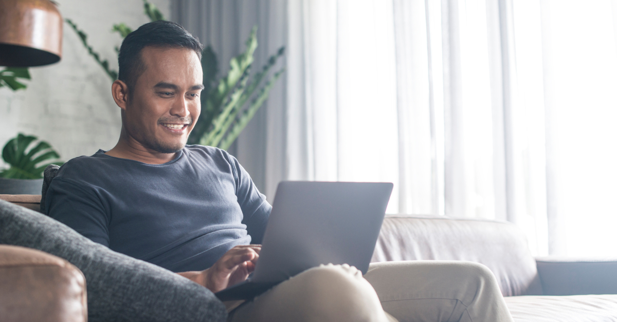 man happy on couch on laptop