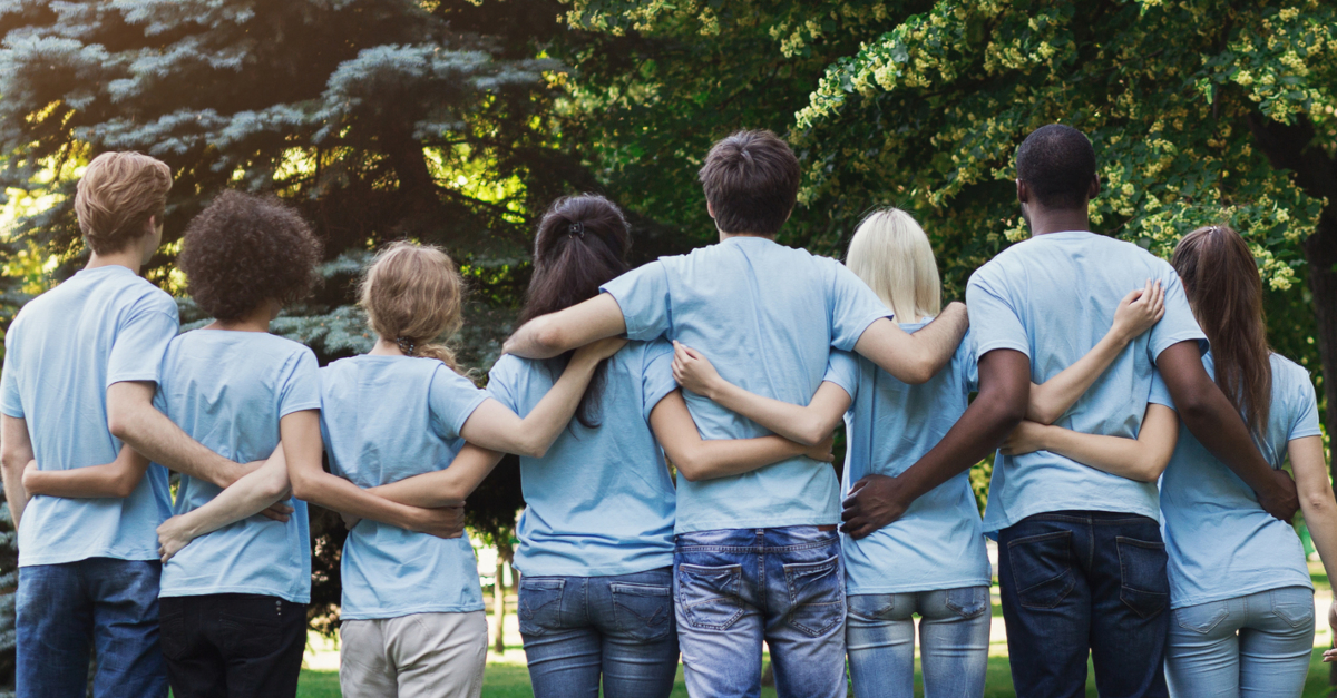 back view of diverse adult volunteers in group hug in a row