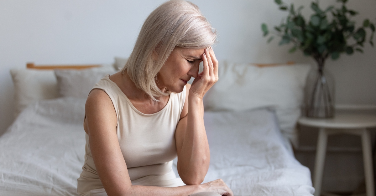 senior white woman looking ill or in pain sitting on bed