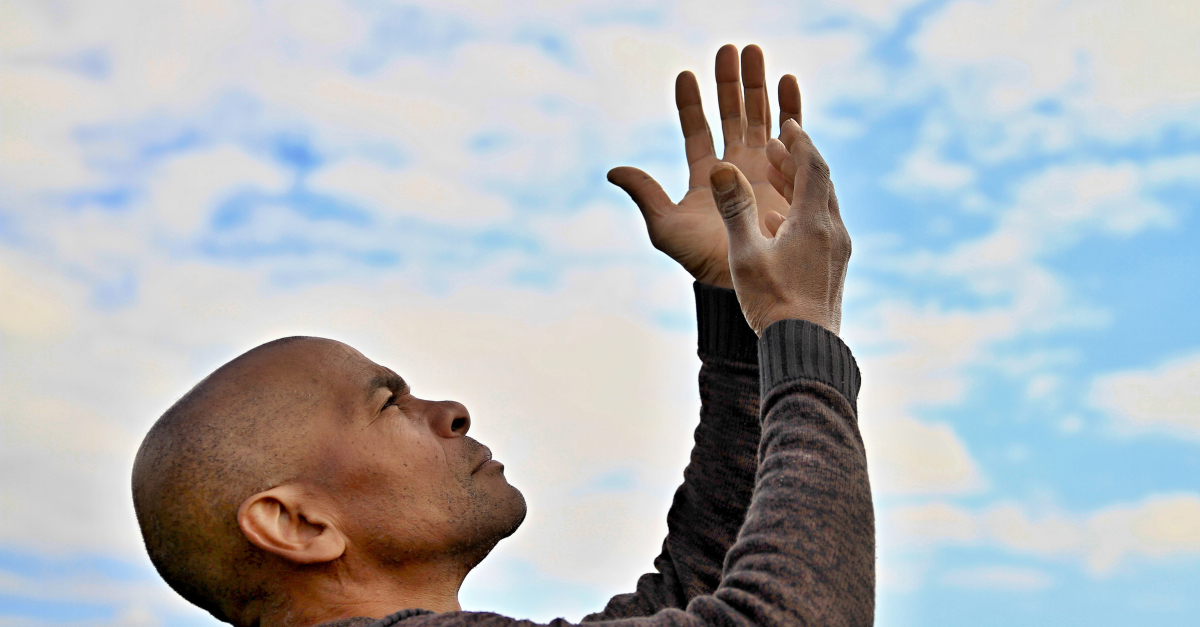 man with arms up to blue sky praise God