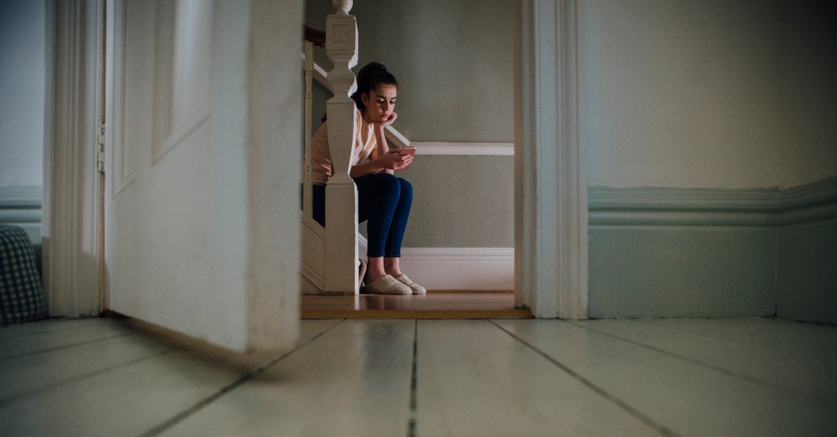 girl on her phone sitting alone on stairs