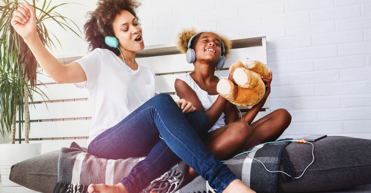 joyful mom and daughter singing praise songs with headphones on