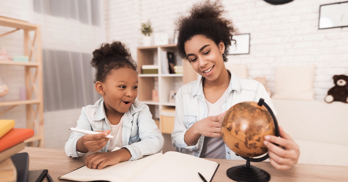 Mom showing her daughter a globe during homeschooling