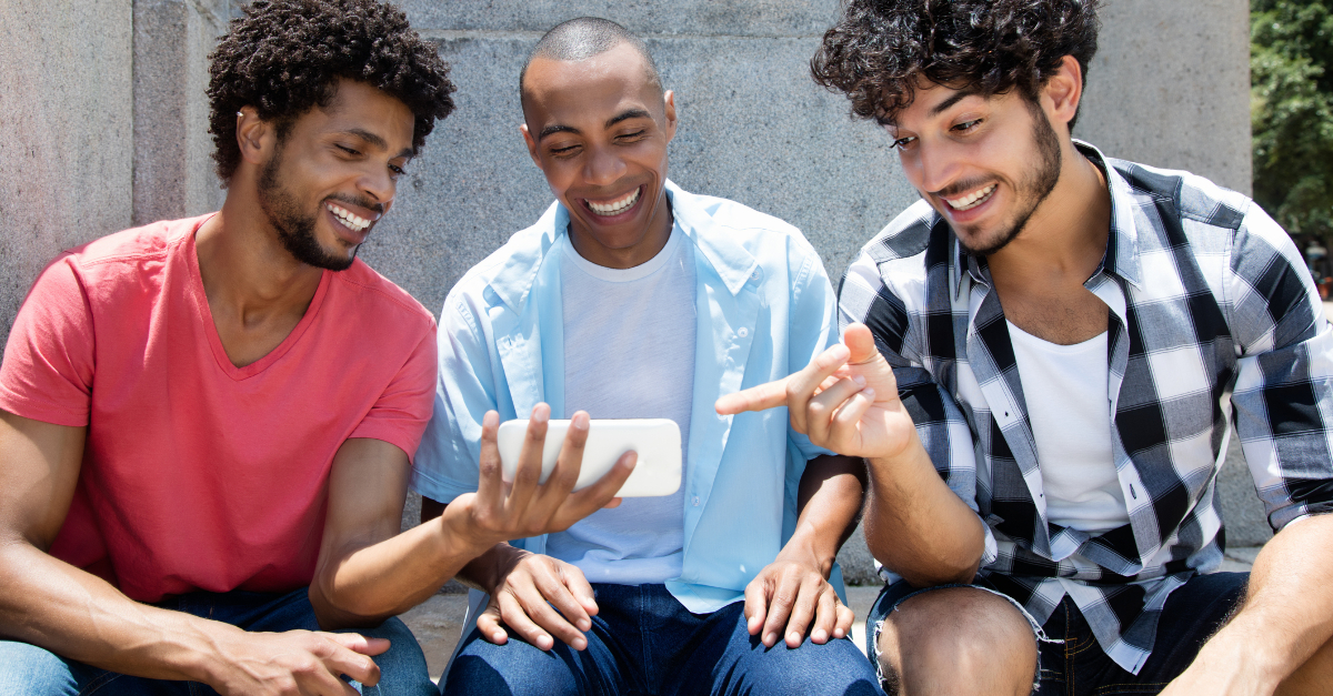 three friends laughing at TikTok video on cell phone