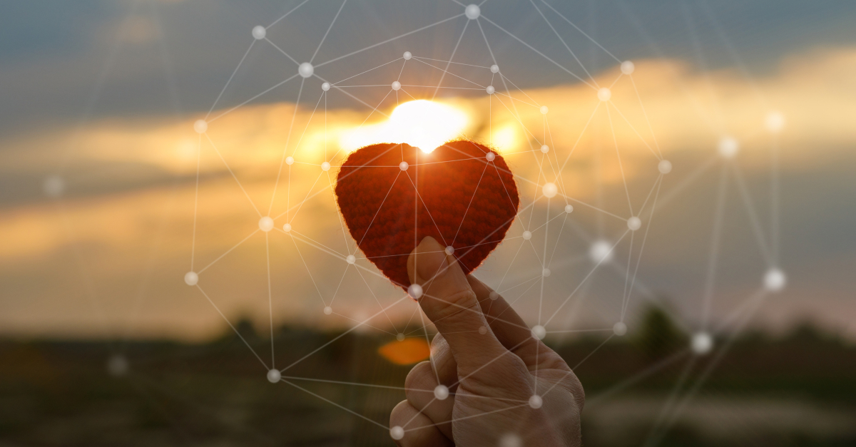 hand holding red knit love heart at sunset