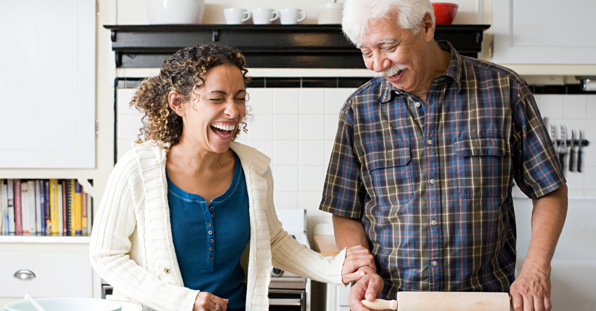 senior dad and adult daughter baking together laughing